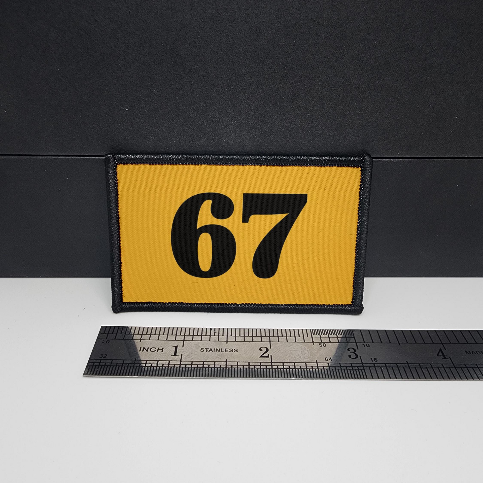Yellow patch with the number 67 on a black background, measured against a ruler.

CAPS LOCK ORIGINAL - morale patch - 2x3 inch – hook and loop - iron-on - interchangeable patch - hat - bag