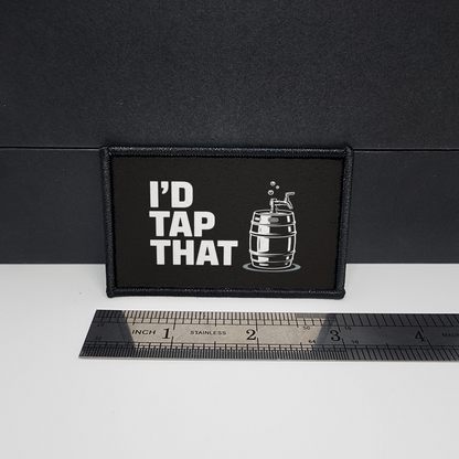 Black patch with 'I'd Tap That' text and a barrel graphic on a white surface with a ruler for scale.