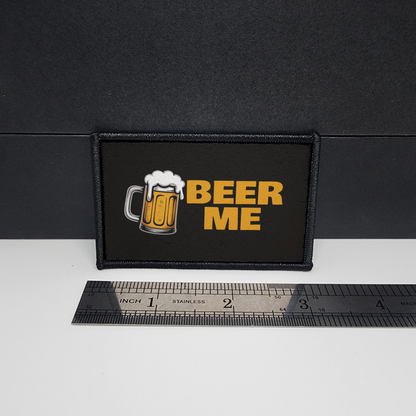 Patch with 'Beer Me' text and a beer mug graphic on a black background, next to a ruler for scale.
