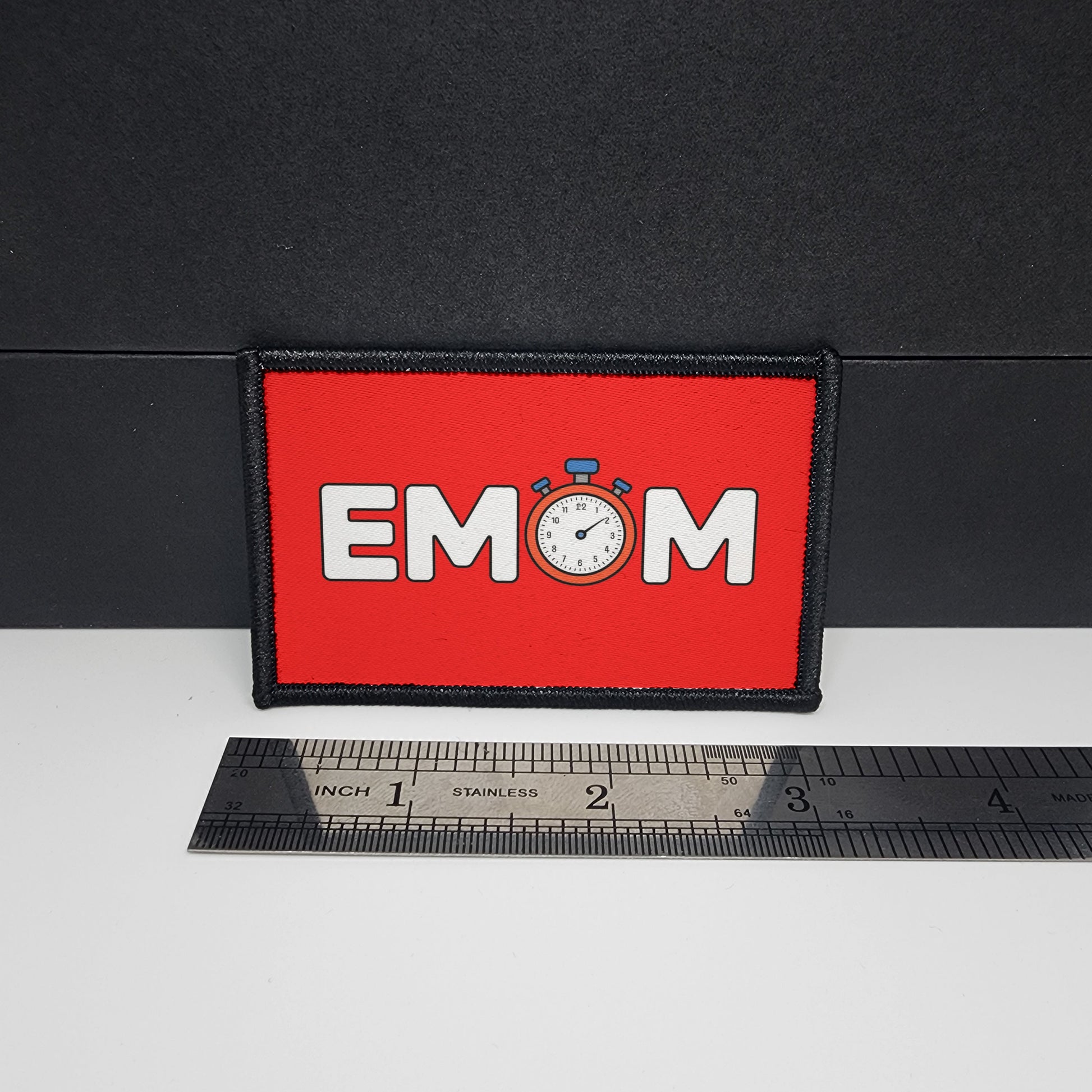 Red patch with 'EMOM' text and a clock graphic on a black surface with a ruler for scale.

CAPS LOCK ORIGINAL - morale patch - 2x3 inch – hook and loop - iron-on - interchangeable patch - hat - bag - sports