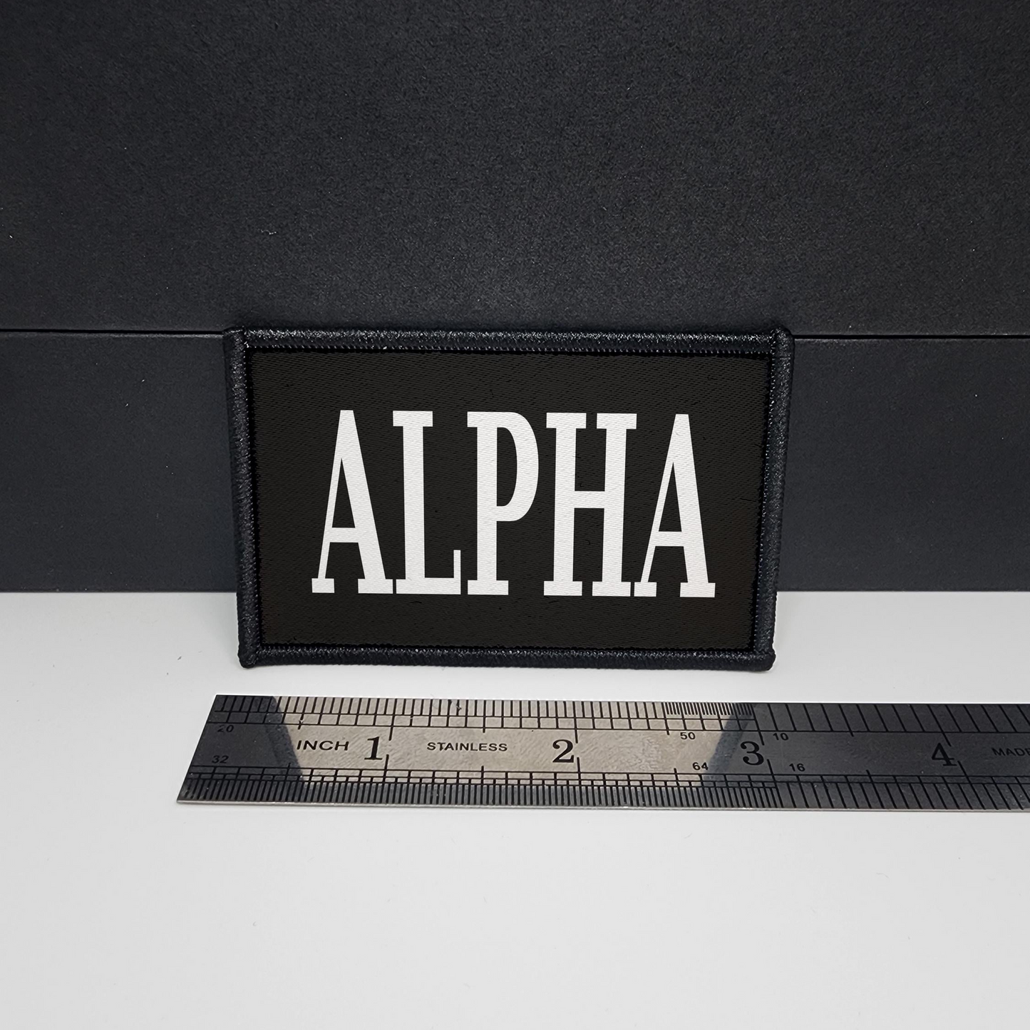 Black patch with 'ALPHA' text on a white surface with a ruler for scale.

CAPS LOCK ORIGINAL - morale patch - 2x3 inch – hook and loop - iron-on - interchangeable patch - hat - bag