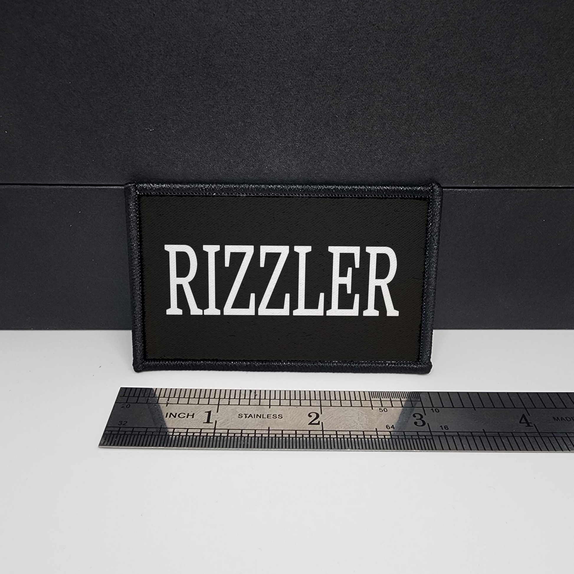 Black patch with 'Rizzler' text on a white surface with a ruler for scale.

CAPS LOCK ORIGINAL - morale patch - 2x3 inch – hook and loop - iron-on - interchangeable patch - hat - bag